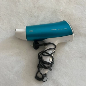 Braun Creation Satin Ions 1900 - Kraftfull hårfön från Braun med satin ions-teknologi och 1900W effekt. Snygg blå och vit design, synligt i gott skick utan större slitage. Perfekt för snabb och skonsam hårtorkning. Levereras med sladd och EU-kontakt. Säljer då jag har fått en ny.