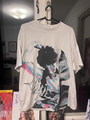 Billie Eilish t-shirt H&M S - Säljer en vit Billie Eilish t-shirt från H&M i storlek S. T-shirten har ett stort grafiskt tryck med Billie Eilish i svart, blått och rosa på framsidan. Modellen är kortärmad och har en loose passform. Materialet är mjuk bomull, perfekt för dig som gillar streetstyle och coola prints.