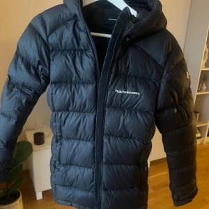 Svart dunjacka Peak Performance XS - Svart dunjacka från Peak Performance. Storlek XS, dammodell. Peak performance jacka W frost DJ. Inga skador, väldigt fint skick.