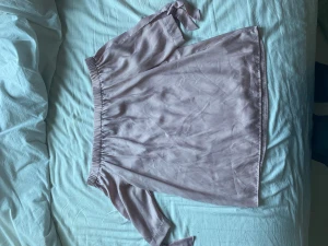 Ljuslila/rosa offshoulder blus - Säljer en ljuslila/rosa offshoulder blus i väldigt skönt material. Toppen har trekvartsärmar med knytband. 