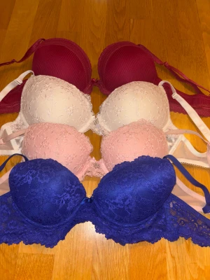 Mix av spetsiga och ribbade bh - 60kr st, alla 200kr. Säljer flera bh i olika färger: marinblå spets, vinröd ribbad, rosa spets och vit spets. Alla har vadderade kupor och justerbara axelband. Spetsmodellerna har blommiga detaljer och meshpartier, medan den vinröda har diskreta ränder och spetskant. 