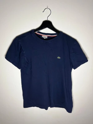Lacoste t-shirt mörkblå - Mörkblå Lacoste t-shirt i mycket bra skick, pm vid intresse.  Storlek: 176cm