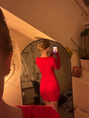 Röd tight kortklänning med v-ringning - Säljer en röd klänning med långa ärmar med  v-ringning. Materialet är stretchigt och skönt