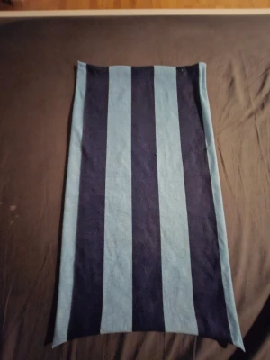 Från djurgårdens butik - Säljer en kortkjol med breda vertikala ränder i ljusblått och mörkblått. Kjolen har en rak och enkel form, perfekt för att skapa en cool och avslappnad look. Materialet känns mjukt och bekvämt mot huden. Passar dig som gillar att sticka ut med grafiska mönster.