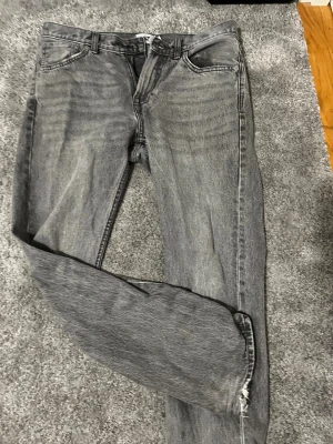 Grå jeans från 157, straight fit - Säljer ett par grå jeans från 157 i klassisk straight fit. De har fem fickor, dragkedja och knappstängning, samt bälteshällor. Jeansen har en tvättad look och är tillverkade i slitstarkt bomullsmaterial. Perfekt för dig som gillar en enkel och clean stil.
