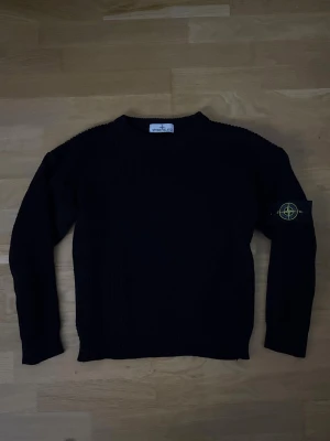 Svart stickad tröja från Stone Island - Svart stickad tröja från Stone Island med klassisk rund hals och ribbad struktur. Tröjan har långärmade och den ikoniska Stone Island-loggan på vänster ärm. Perfekt för dig som gillar stilrena och tidlösa plagg. Kan gå ned i pris vid smidig affär. Om fler bilder önskas är det bara att skriva.