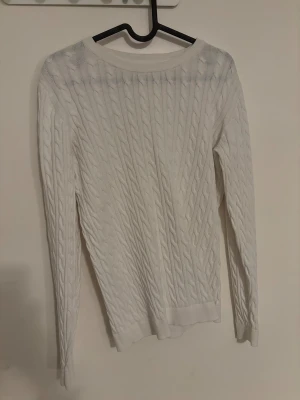Vit kabelstickad tröja - Snygg vit kabelstickad tröja med rund hals och långa ärmar. Tröjan har ett klassiskt flätmönster som ger en stilren och fräsch look. Perfekt att matcha med jeans eller kjol för en chill och clean outfit. Endast använd en gång. Storlek M. Hör av dig via e-mejl eller mobilnummer då jag inte kan ta emot Swish på detta nummer. E-mejl emli.com@icloud.com mobil-0728875624 mvh Emilia/marina😊