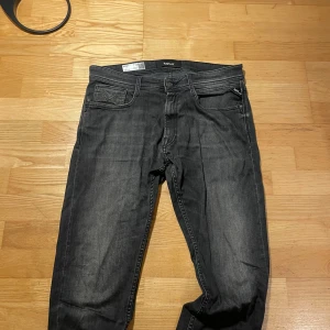 Svarta Replay jeans Rocco comfort fit - Säljer ett par svarta Replay jeans, modell Rocco comfort fit. Jeansen har klassisk femficksdesign, svarta sömmar och Replay-logga på bakfickan. Materialet är jeans och passformen är relaxed och bekväm. Perfekta för dig som gillar en stilren look.