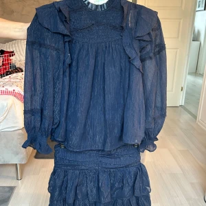 Mörkblå volangkjol,  mörkblå matchande blus  - Supersöt mörkblå blus med en matchande mörkblå kjol. Om man vill köpa båda kostar det 350kr och om man vill köpa en utav dom kostar de 200kr/st. Använd en gång