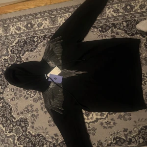 Svart Marcelo Burlon Hoodie - Lyxig hoodie från Marcelo Burlon County of Milan, med det välkända vingtrycket i silvergrått över bröst och axlar – en riktig streetwear-ikon! Denna kommer verkligen att attrahera brudarna! 🙌  ✔️ Äkta designerplagg ✔️ Detaljerad vingdesign som sticker ut ✔️ Bekväm passform och hög kvalitet