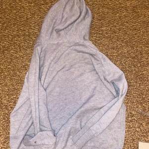 Ljusgrå hoodie med snörning merinoull  - En stilren ljusgrå hoodie med snörning i huvan och ribbade muddar. Perfekt för dig som gillar en enkel och clean look. Mjuk och skön, passar till allt och är ett måste i garderoben.