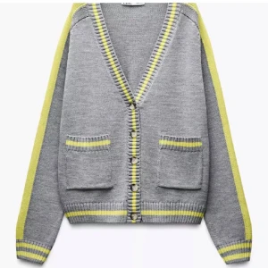 Grå kofta med gula ränder från Zara - Grå kofta från Zara med gula ränder längs ärmar, muddar och kanter. V-ringad med knappar framtill och två fickor. Helt slutsåld på hemsidan och går inte att få tag i därav priset