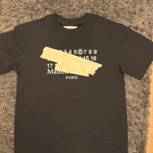 Svart t-shirt Maison Margiela  - Svart t-shirt från Maison Margiela Paris med ikoniskt tryck av siffror. Pris kan diskuteras 