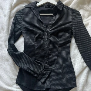 Svart skjorta  - Super fin svart skjorta med vita tunna ränder. Tight och går in vid midjan. Säljer då den är för liten för mig. 