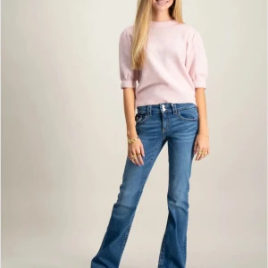 Blå bootcut jeans med låg midja - Snygga blå jeans med bootcut och låg midja. Jeansen har klassisk femficksdesign, dragkedja och knapp framtill samt lätt tvättad look. Perfekta för dig som gillar en retrostil med utsvängda ben.