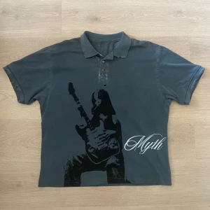 Distressed pikéskjorta - Med coolt tryck! Passar M/L. Litet hål under knapparna. Den är blågrå