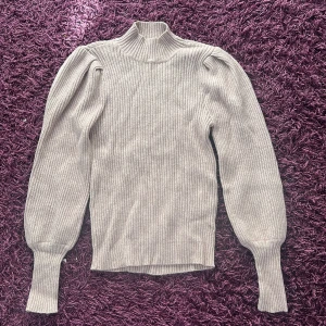 Beige, lila, grå ribbad stickad tröja ONLY XS - Supersnygg beige ribbad stickad tröja från ONLY i storlek XS. Tröjan har puffiga axlar, lång ärm och hög hals för en trendig look. Perfekt till höst och vinter, och passar till både jeans och kjol. Den är mer lila i verkligheten.