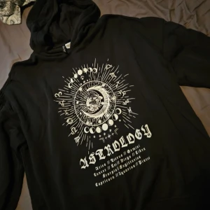 Svart hoodie - Svart hoodie från Divided by H&M i storlek XL med stort vitt astrologitryck framtill. Tröjan har huva och långa ärmar, perfekt för dig som gillar mystiska vibes och coola prints. Mjuk insida och klassisk passform.