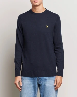 Mörkblå stickad tröja från Lyle & Scott - Snygg mörkblå stickad tröja från Lyle & Scott med klassisk gul broderad fågel på bröstet. Rund hals, ribbade muddar vid ärmslut och nederkant. Perfekt för dig som gillar stilrena och enkla plagg med en touch av märke.