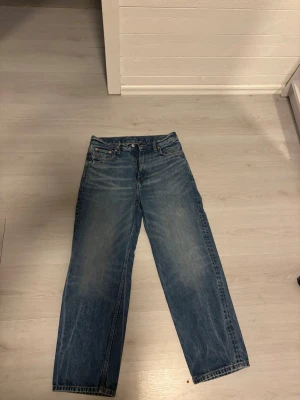 Weekday blå straight jeans W28 L30 - Säljer ett par blå Weekday Galaxy Loose Straight Jeans i klassisk tvättad denim. Modellen har raka ben, normal passform och fem fickor. Perfekt för dig som gillar en avslappnad och tidlös stil. Materialet är 100% bomull. Knappt använda! 
