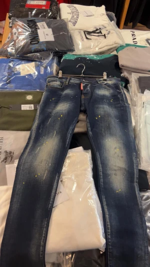Dsquared2 skinny jeans med färgstänk - Jag har alla storlekar på dessa jeans!!  Snygga blå skinny jeans från Dsquared2 med coola färgstänk i gult och rött samt slitna detaljer. Jeansen har klassisk femficksdesign, låg midja och är tillverkade i stretchig bomull med lite polyester för extra komfort. Perfekt för dig som gillar streetstyle.
