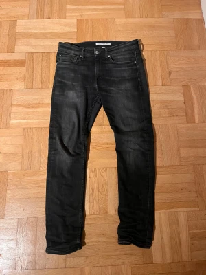 Svarta slimfit jeans från Calvin Klein - Snygga svarta jeans från Calvin Klein Jeans med diskret tvättad look och klassisk femficksdesign. Modellen är skinny med slim passform och har en tydlig logotyp på bakfickan. Perfekt för dig som gillar stilrena och moderna jeans.