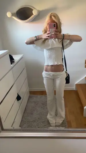 Säljer ett par vita lågmidjade byxor med bootcut-snitt . Byxorna har en rak och lite utsvängd passform nedtill, vilket ger en snygg siluett. Materialet ser ut att vara mjukt och bekvämt, perfekt för en chill och trendig look.