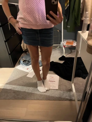 Blå jeanskjol från Never Denim - Säljer en snygg blå jeanskjol från Never Denim. Kjolen är kort, har rå kant nertill och klassiska jeansfickor både fram och bak. Perfekt passform med normal midja och bälteshällor. Enkel och stilren design som är lätt att matcha. Använd 1 gång 