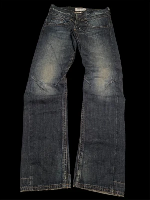 Blå wideleg archive jeans - Snygga blå jeans med bootcut passform och slitna detaljer. Klassisk femficksmodell med kontrastsömmar och läderpatch bak i midjan. Jeansen har en cool tvätt och är tillverkade i mjukt denimtyg för skön känsla. Full length 110cm, waist 44cm.