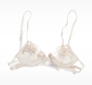 Spetsig vit korsett från La Perla - Säljer en superfin vit behå från La Perla med tunna axelband och vacker spetsbroderad mesh. Den har delikata blommiga detaljer och transparenta partier som ger en lyxig känsla. Perfekt för dig som gillar exklusiva underkläder med romantisk vibe. Storlek liten.