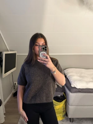 Mörkbrun stickad t-shirt - Mysig mörkbrun stickad t-shirt med korta ärmar och rund hals. Tröjan har en avslappnad passform och är perfekt att styla med jeans.