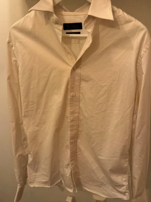 Vit skjorta från Riley Slim Fit - Klassisk vit skjorta från Riley i slim fit-modell. Skjortan har långa ärmar, knappar framtill och en stilren krage. Perfekt för dig som gillar en enkel och clean look. Tillverkad i mjuk bomull för skön känsla hela dagen.