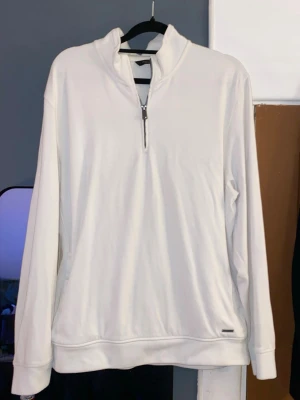 Vit half zip sweatshirt - Säljer en stilren vit sweatshirt med half zip och hög krage. Tröjan har lång ärm och en relaxed passform, perfekt för dig som gillar en clean och enkel look. Materialet känns mjukt och skönt mot huden.