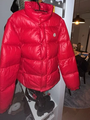 Moncler Andersen   - Röd Andersen i storlek 5 använda en vinter men är fel fri, sista bilden så ser ni även en dragkedja i armen det menas att den går även att ha som väst.  Passar perfekt och är skit skön nu i kalla vintern.