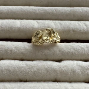 Rostfritt ring  - Säljer en superfin och unik ring i guldplätering. Den har en organisk, skulptural design som verkligen sticker ut. Perfekt för att ge din outfit en extra touch av elegans. Ringen är justerbar, så den passar de flesta storlekar. Perfekt för både vardag och fest!