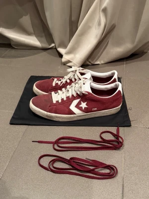 Vinröda Converse CONS sneakers mocka - Säljer ett par vinröda Converse CONS sneakers i mocka med vita detaljer och snörning. Skorna har vit sula, klassisk stjärnlogga på sidan och kommer med extra vinröda skosnören. Storleken är egentligen 46,5 men sitter mer som 45,5-46 beroende på önskad passform!! Mitt pris är 440! Hör av dig vid minsta fråga! 