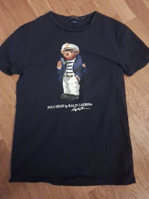 Svart Polo Bear t-shirt från Ralph Lauren - Säljer en mörkblå t-shirt från Ralph Lauren med Polo Bear-tryck framtill. T-shirten har rund hals och korta ärmar