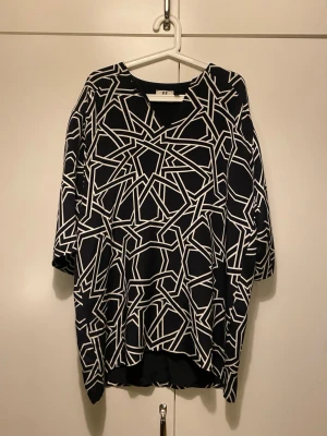 Svartvit mönstrad blus från Topshop - Snygg svart blus från Topshop i storlek 34 med grafiskt vitt mönster. Tillverkad i 100% siden för en lyxig känsla. Blusen har trekvartsärm och en avslappnad passform. Jag har annars storlek 36 och kan ha denna utan problem. 