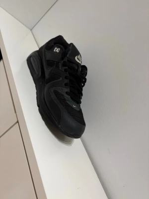 Svarta Nike Air Max sneakers - Säljer ett par helsvarta Nike Air Max sneakers med mesh och syntetpaneler. Klassisk Nike-logga på plösen och sidan, samt synlig Air-dämpning i sulan. Skorna har snörning och en chunky, sportig look som passar till streetwear.