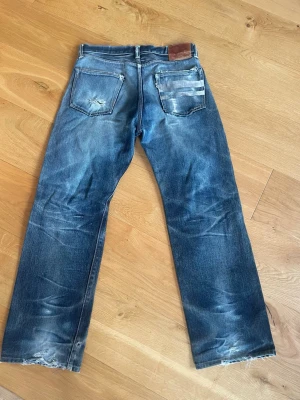 Momotaro blå jeans med slitningar - Säljer ett par blå jeans från Momotaro med sjuka fades. Lappen säger 32/32 men sitter mer som W 30 L 32 