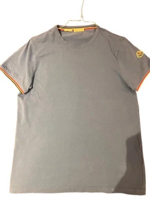 Ljusblå t-shirt från Moncler äkta! - Snygg ljusblå t-shirt från Moncler med korta ärmar och rund hals. Diskret Moncler-logga på ärmen och  detalj på insidan av kragen samt vid ärmslut. Äkta givetvis och dunder pris💪