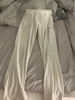 Ljusbeige mjukisbyxor med fickor - Säljer ett par vita juicy byxor med bred resår i midjan och två stora fickor framtill. Byxorna har snören som åkt in i hålen men går att dra ut. Sköna och perfekta för chill dagar hemma eller på stan.