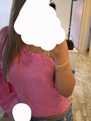 Rosa oneshoulder topp - Trendig rosa oneshoulder topp med lång ärm och croppad passform. Perfekt för dig som vill sticka ut med en färgglad och modern stil. Tunnare material som känns skönt mot huden.