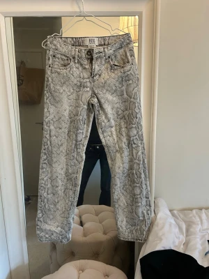 ormmönstrade jeans från urban outfitters - Säljer ett par grå/vita jeans från BDG Urban Outfitters med ormmönster. Jeansen har rak avslappnad passform och normal midja. Perfekta för dig som vill sticka ut! ✌️🦄 Aldrig använda! 