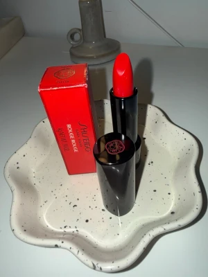 Shiseido Rouge Rouge - Shiseido Rouge Rouge – Poppy (NY)  Helt nytt och oanvänt läppstift från Shiseido Serie: Rouge Rouge Nyans: Poppy Mängd: 4 g  Endast öppnad för fotografering, aldrig testad. Originalförpackning medföljer.  Nypris ca 350–400 kr