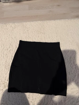 Svart minikjol med slits - Enkel och stilren svart minikjol med en liten slits på sidan. Ursprungligen köpt från zalando. Kjolen har en rak passform och är perfekt för att skapa en clean look. Ordpris: 299kr säljer för 40kr plus frakt