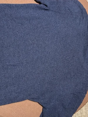 Mörkblå kashmirtröja från Uniqlo - En stilren mörkblå tröja från Uniqlo i mjuk kashmir. Klassisk rund halsringning och långärmad modell som passar perfekt till lager på lager under höst och vinter. Enkel och clean design utan mönster eller detaljer. Nästan helt ny