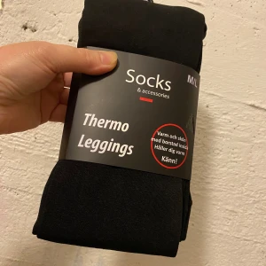 Svarta thermo leggings M/L - Svarta thermo leggings från Socks & accessories, perfekta för kalla dagar. Tillverkade i 95% polyester och 5% elastan med borstad insida som håller dig varm. Stretchigt material och bekväm passform, passar dig som vill ha både stil och värme.