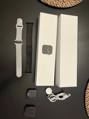 Apple Watch Series 5 44mm GPS + Cellular - Apple Watch Series 5 44mm GPS + Cellular i aluminium. Inkluderar originalförpackning, laddare och två armband. Klockan har synliga repor och sprickor på skärmen men är fullt fungerande. Perfekt för dig som vill ha en smartklocka med många funktioner till ett bra pris.