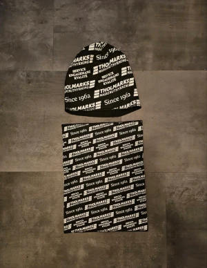 Mössa och halsvärmare  - Säljer ett set med svart och vit mössa och matchande halsvärmare från Tholmarks. Båda plaggen har ett tryckt logomönster med texten 'Since 1962". Tillverkade i mjuk polyester som passar perfekt för kyliga dagar.
